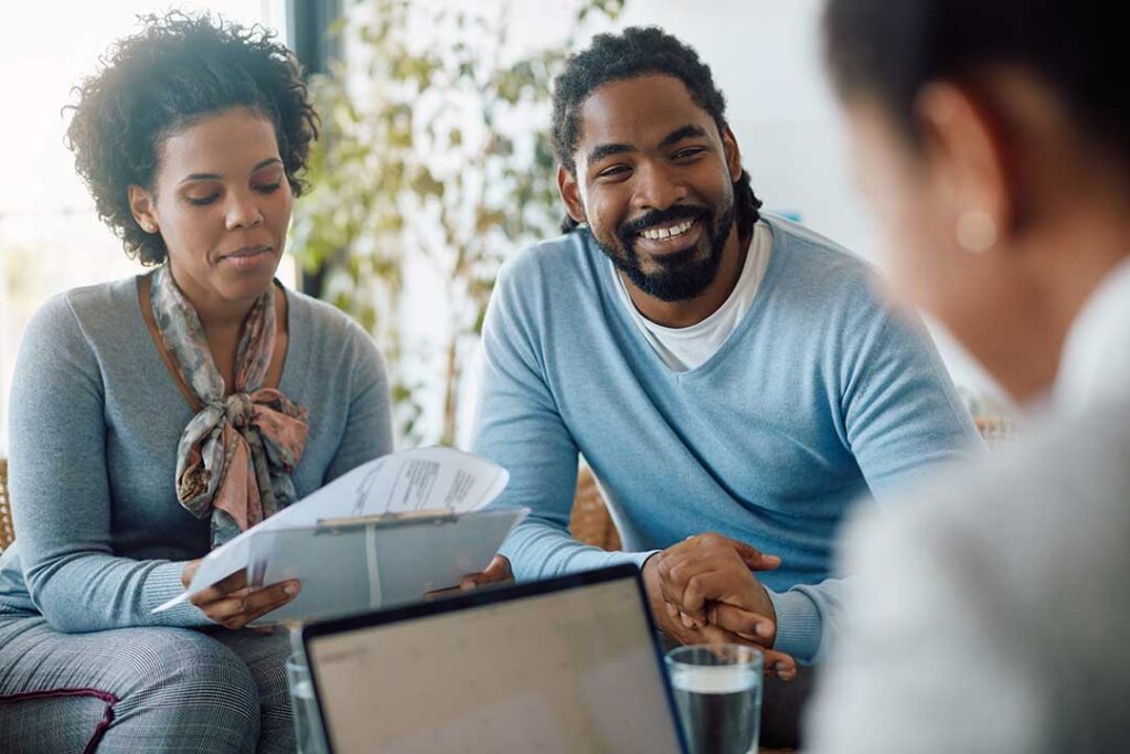 Homebuyer reviewing mortgage documents and a payment worksheet at a kitchen table.