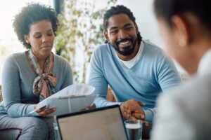 Homebuyer reviewing mortgage documents and a payment worksheet at a kitchen table.